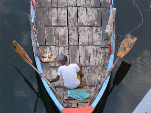 A boatman prepares to go to his 'office' - the holy side of the river where the temples are to take devotes on a ride in the holy river. An everyday routine for the few boatmen still left of this dying profession.