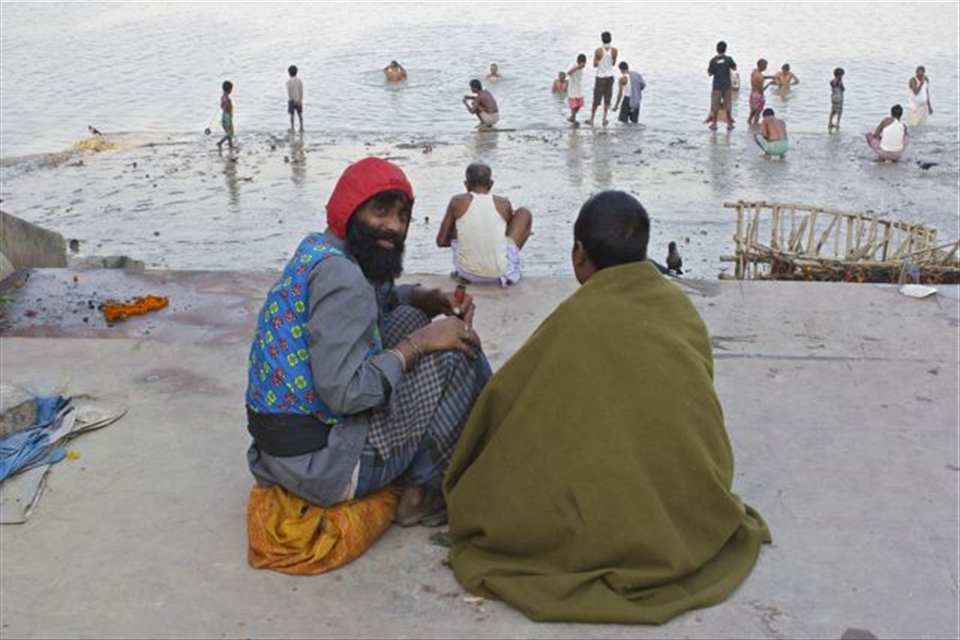 Two friends enjoy a homemade bong while watching men bathe in the Hooghly River