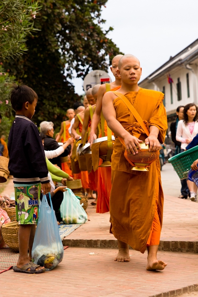A young boy begs for food from a passing Buddhist monk.