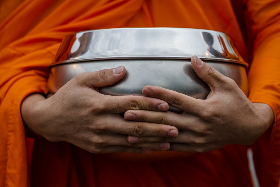 Buddhist monks blesses you as you give them an offering of food in a daily ritual. The bowl holds the goods you give them. In Thailand monks are not vegetarian, because they eat what ever the people give them.  