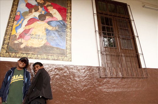 As they watch the rain pour in the courtyard, two boys have a laugh in the corne