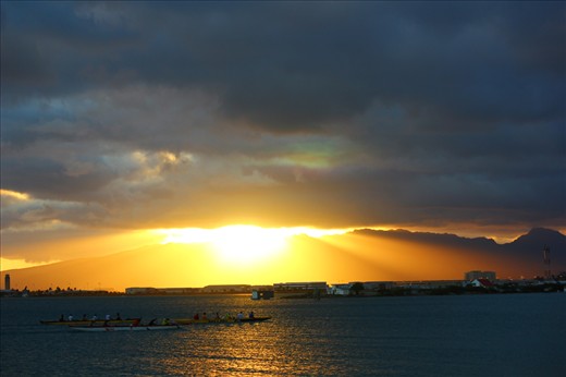 Locals practicing their paddling as the sun sets over the Oahu mountains.