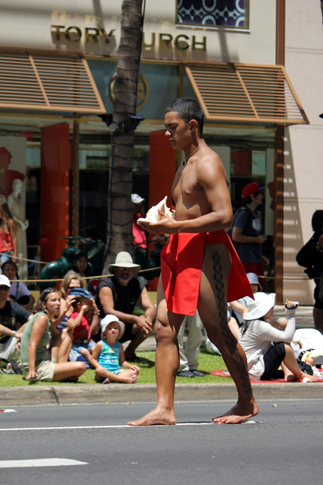Barefoot parade marshall walks on white lines for respite from the asphalt heat.