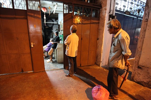 Passersby join in in watching a TV show with a family living in a storefront.