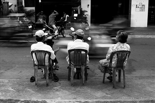 Locals sit and relax by the edge of the road.