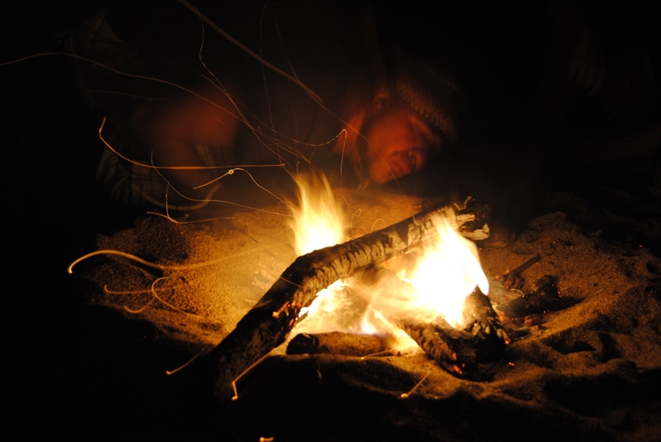 The fire dances at the rhythm of the beats and chords during a North Shore bonfire night. Warm and appealing waters in the dark and dangerous ocean seduce swimmers to dive in its shore. The ex-marine blows for light and heat as the wind copies him to caress the bare feet of the present souls. Good vibes and peacefulness embrace the everlasting dimness. 