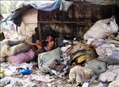 A man listens to music as he lounges on a shabby sofa amidst mountains of trash: by photoforager, Views[243]