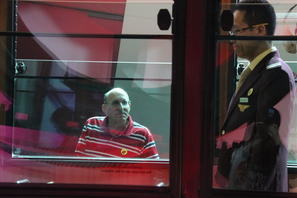 Hong Kong, China, an American tourist following  driver's every move like a hawk while the cable car is starting its climb up the steep slopes of the highest peak in the new land of opportunity and fortune. All eyes are in Asia, this is the part of the world that worries America the most and to where people and businesses from all over the world are now gathering in the hopes of fast money. The fear reflects America's own insecurities and prejudices towards growing economies, the fear of loosing the last remains of its hegemony. What needs to be decided is whether to take the globalization as a threat or possibility!