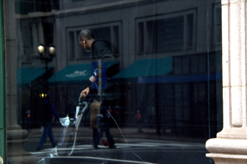 Philadelphia, United States of America, a man, eaten by the darkness, vacuuming a shop window while the busy city life reflects from the glass that separates him from the rest of the world in the center of liberty and independence. The ones with a job can consider themselves lucky and many are working long hours with just a minimum wage. People are trapped in debt slavery, while leading a double life, and trying to keep up their facades. Opportunities are a rare when the jobs are moving to the cheaper and more productive countries. USA, only a reflection of what it used to be, is in crises.