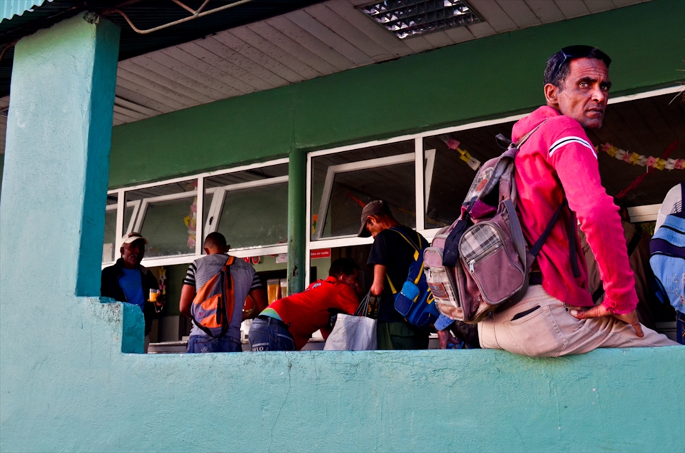 A reddish brown colored skin man sits in front of a Juice Bar in Matanzas downtown. In his green glance there’s a mirror of the daily struggle of all Cuban, loving their homeland but, in the words of some, “surviving” and willing to leave the island by all means: selling their cars, getting more money by having 3 or more jobs and asking for economic favors to their relatives outside Cuba. He seems he is looking daggers at the harsh present and the inexistent future of a just retirement; always a melancholic look in the eyes of the islanders.    