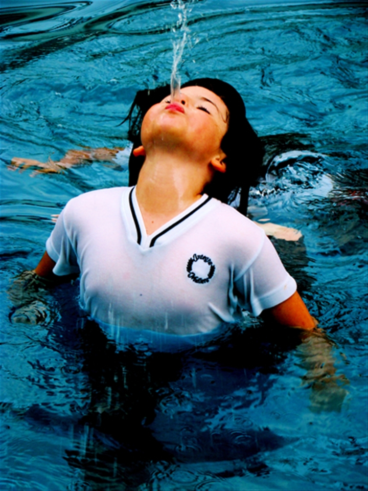 A school girl, hot summer day, doesn't care jumps in the water in her uniform