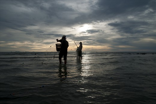 two people catching fish using nets, in local language called 