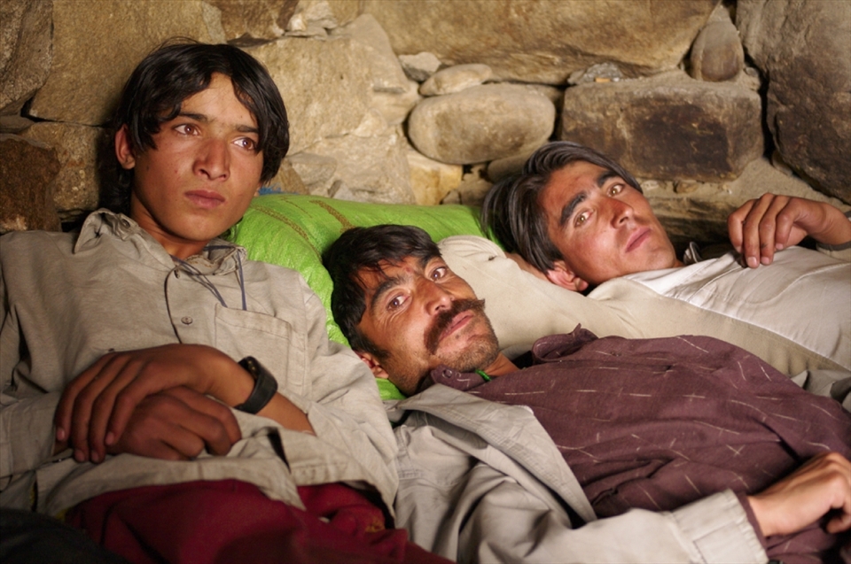 Three friends relax together in a shelter on the Baltoro glacier. Away from their families for weeks at a time, the men sleep in crude stone shelters with plastic sheeting for a ceiling, sleeping huddled together under old sleeping backs for warmth.