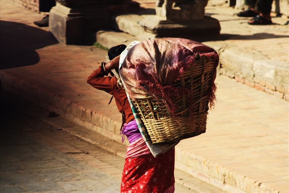 With a heavy load on her back, a woman carries much needed goods to her family
