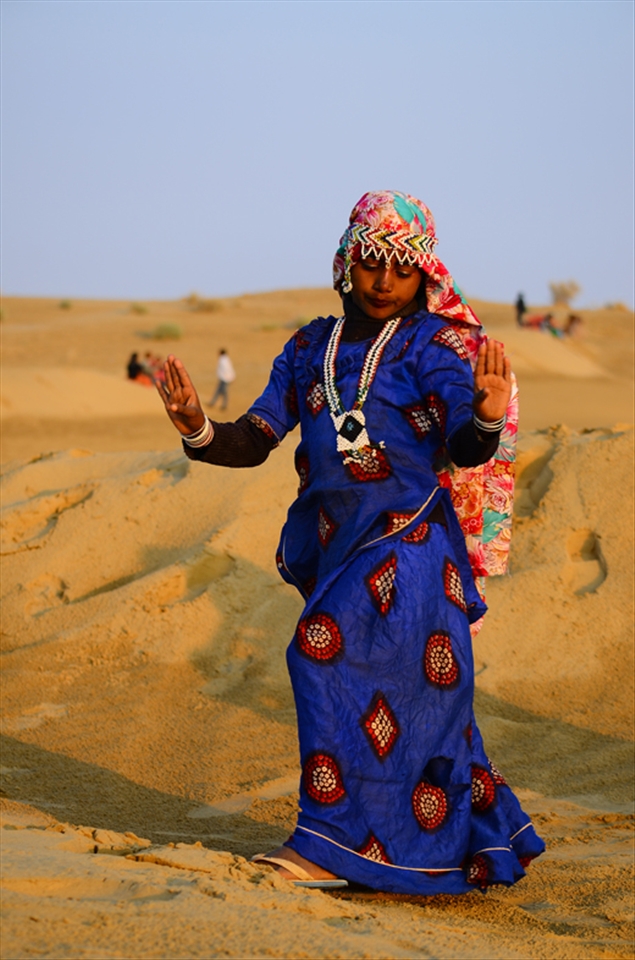 Tribal girl dancing and entertaining people to earn money at Sam Sand Dunes