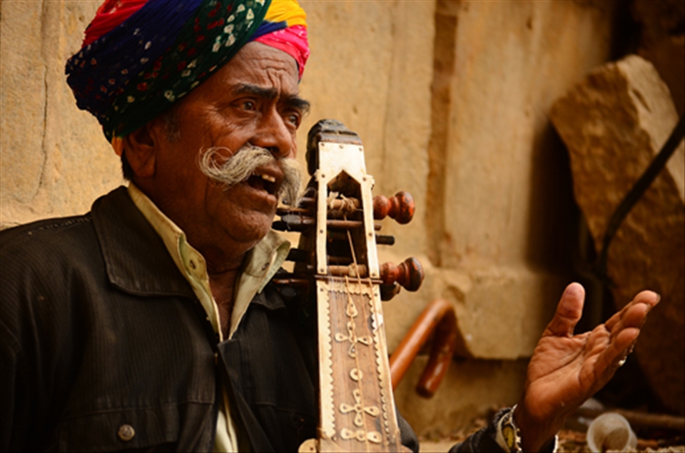 An old man playing traditional musical instrument to entertain people.