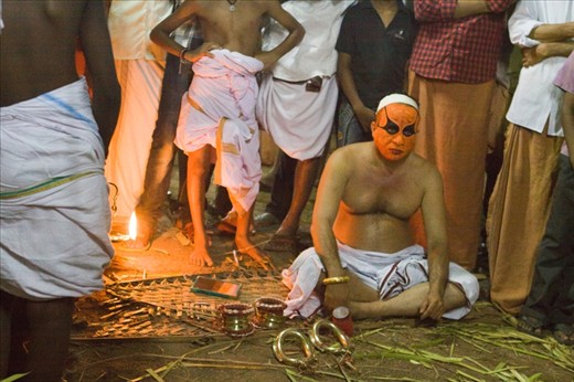 Contemplation: A Performer waits in anticipation after his first round of makeup. Becoming a Theyyam performer is physically and mentally challenging.