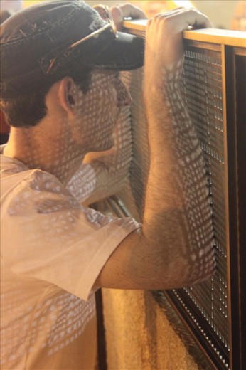 It is an amazing sight at the end of Shabbat to see hundreds of Jewish people flocking the Wailing Wall to pray silently. They are joined by stony faced security forces and bemused looking tourists. This tourist was standing on the opposite side of the security fence surrounding the wall area, watching proceedings. I took the picture as I loved the expression on his face coupled with his pose, and also I love the way the light filtering through the fence strikes the subject. (feat. Simon O'Meara)