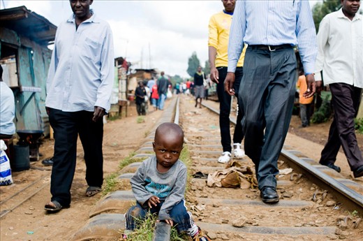boy is sitting on the railtrack in Kibera. the old railtrack is still in service