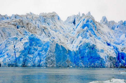 Seagulls and other birds -tiny looking- fly low in front of millions year old ic