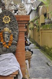 A shrine to a Balinesian god is on a wall near an alley with a motor bike in the background showing how the Western world and tourism has influenced the Balinesian culture.  Now it is a mix between modern ameneties like motor bikes and keeping with the traditional culture in Bali.: by rachelmarek, Views[688]