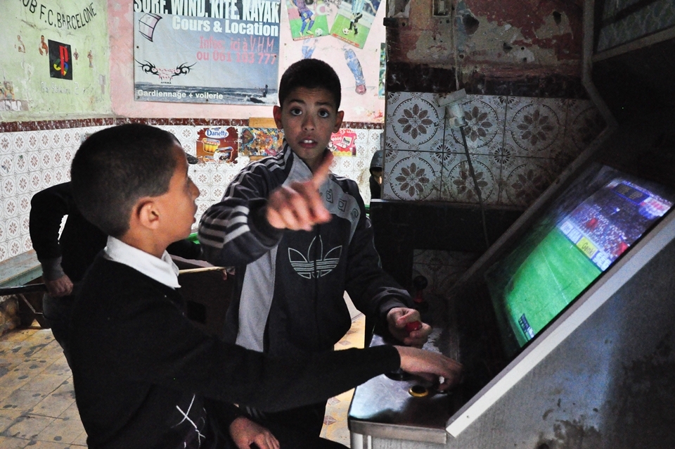 A little boy who doesn´t want to be photographed. Essaouira, December 2012 - As in Marrakech, as well in Essaouira we often met the children on the streets who went from school after which they was playing usually with a ball. In this city we found the place inside one of the many old buildings where were lot of kids „playing“ games on the games machines. It was interesting, and a little bit sad for me, they didn´t have a coins for the games, so in fact they didn´t play a real game, just watched the previews of the game. But still it is better as do the homeworks, or isn´t it? Kids are the same everywhere...