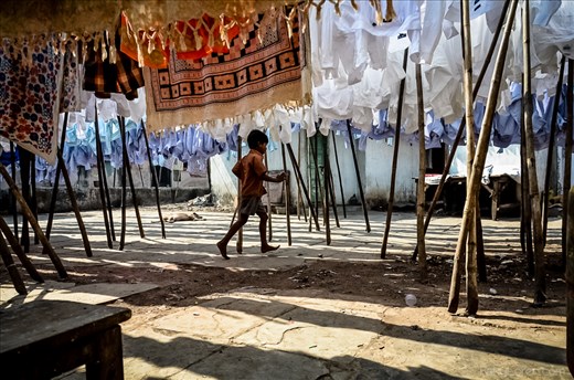 A young boy runs through a courtyard of dwellings within the laundry community.