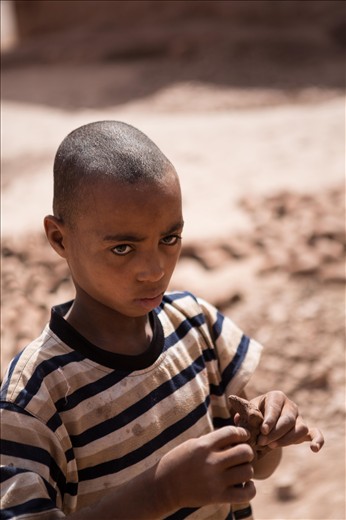 Child building a small mud horse in the harsh sunlight