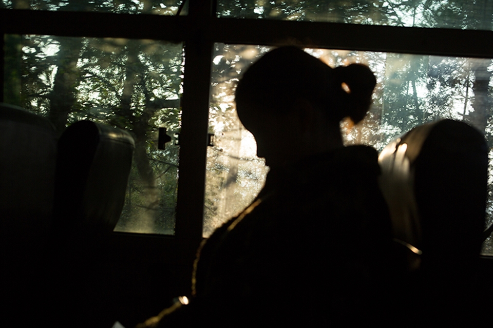 Yu on the bus with sun setting outside 