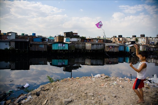 A boy plays with his kite on top of a pile of rubble