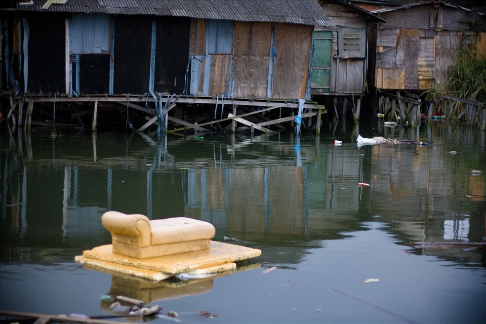 A piece of couch floats on the polluted river