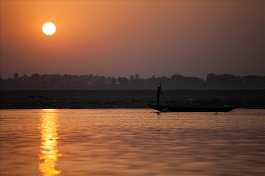 Young men begin working at sunrise by boat on the River Ganges.