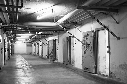 Genslerstrasse, Berlin. Tucked away in a leafy Berlin suburb lies an unassuming compound surrounded by guard towers and barbed wire. Formerly an infamous Stasi prison, it is now home to the Berlin- Hohenschönhausen Memorial. 
Stepping through the heavy metal door into one of the cellblocks, the air is cold and damp, and the bright afternoon sunshine outside seems to have been consumed by a much darker world. This particular block was nicknamed the “submarine”, as it is underground and does not get much natural light. 