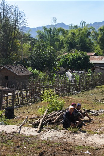 Hanging off the back of a truck with my camera around my neck gave me the best vantage point for this particular drive. Clinging to the support bars with the wind rushing across my face, I was amazed with what I was seeing. We were travelling from the small, one-road town of Bah Nahin to our destination of the Konglor Caves. The pick up truck was full of my travel companions plus the occasional local jumping on board for the ride with their sacks of produce and baskets of live ducks in tow – it seemed we had hitched a ride with the local taxi. As we drove between the dramatic limestone mountains encircling the valleys, we passed countless shacks and huts that made up the rural communities of Laos. This for me was the most authentic Asian experience I could have asked for. Farmers were plowing the fields with their cattle; wood was being gathered while the women were hanging out washing. As we passed the school, hordes of smiling children swarmed out to greet us. “Sa-bai-dee!!” they all shouted, running after the truck as we drove by. Further along our bumpy ride, we happened upon couple of elderly men sitting amongst some wood for what looked like fencing posts. As with everything that day I photographed it. Looking at this photo always reminds me of all of the necessary tasks that are usually just out of sight of my first world perspective.