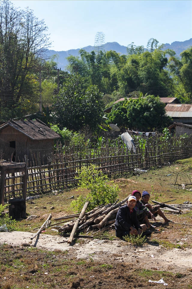 Hanging off the back of a truck with my camera around my neck gave me the best vantage point for this particular drive. Clinging to the support bars with the wind rushing across my face, I was amazed with what I was seeing. We were travelling from the small, one-road town of Bah Nahin to our destination of the Konglor Caves. The pick up truck was full of my travel companions plus the occasional local jumping on board for the ride with their sacks of produce and baskets of live ducks in tow – it seemed we had hitched a ride with the local taxi. As we drove between the dramatic limestone mountains encircling the valleys, we passed countless shacks and huts that made up the rural communities of Laos. This for me was the most authentic Asian experience I could have asked for. Farmers were plowing the fields with their cattle; wood was being gathered while the women were hanging out washing. As we passed the school, hordes of smiling children swarmed out to greet us. “Sa-bai-dee!!” they all shouted, running after the truck as we drove by. Further along our bumpy ride, we happened upon couple of elderly men sitting amongst some wood for what looked like fencing posts. As with everything that day I photographed it. Looking at this photo always reminds me of all of the necessary tasks that are usually just out of sight of my first world perspective.