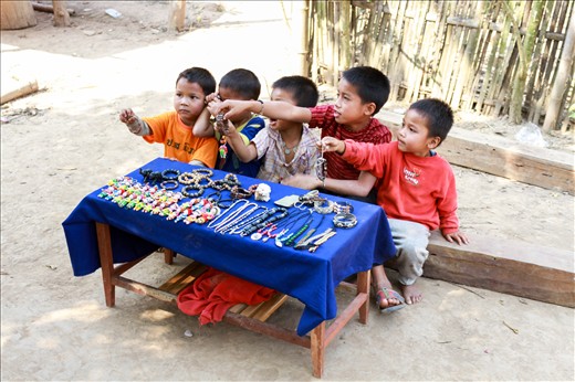 After our boat ride along the Mekong River, we happen to cross a small village not far from the banks of the water. The majority of the occupants were fishing while the kids played in the shallows of the river amongst the pyrite sand. Sitting outside their huts were several locals performing odd tasks like tending to the animals, weaving tapestries to sell in the Luang Prabang markets, or carrying wood from their forages. As we turned a corner, we were greeted by a group of infants selling bracelets and trinkets. They all called harmoniously “Sa-bai-dee!” “Hello!” “Sa-bai-dee!” We all glanced at each other, silently sharing the desperation of the scene together. No one bought a thing and I still wonder if I should have.
