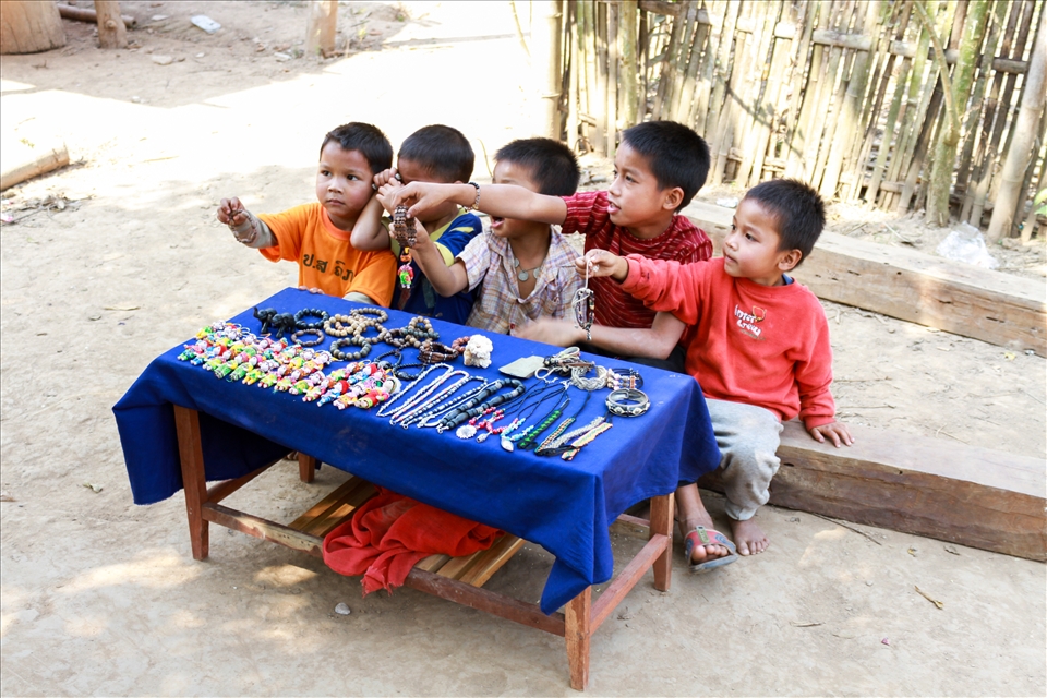 After our boat ride along the Mekong River, we happen to cross a small village not far from the banks of the water. The majority of the occupants were fishing while the kids played in the shallows of the river amongst the pyrite sand. Sitting outside their huts were several locals performing odd tasks like tending to the animals, weaving tapestries to sell in the Luang Prabang markets, or carrying wood from their forages. As we turned a corner, we were greeted by a group of infants selling bracelets and trinkets. They all called harmoniously “Sa-bai-dee!” “Hello!” “Sa-bai-dee!” We all glanced at each other, silently sharing the desperation of the scene together. No one bought a thing and I still wonder if I should have.