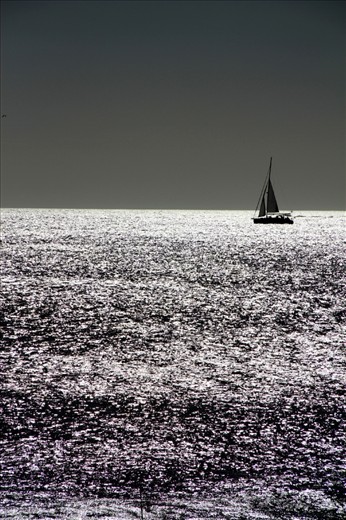 Sailboat seems to be attached  to the sea. Almost like a drawing on the horizon.