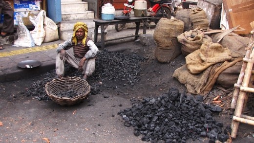 The daily grind: Sifting through charcoal by hand on the busy streets of New Delhi.