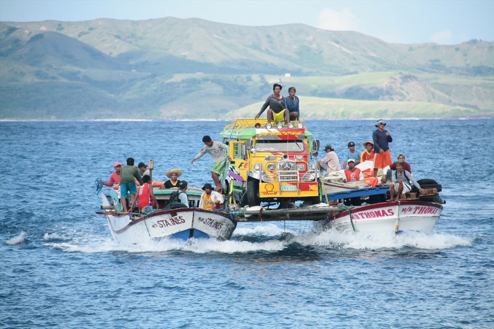 Two fishing boats ferry a jeepney (a common passenger vehicle) to Sabtang Island in Batanes,  The precarious chartered transport costs Php6000 (or approximately US$147) for a one-way trip from nearby Batan Island and has been a local method of transporting vehicles like vans and ambulances between the two northern islands in the province, crossing the vast waters where South China Sea and Pacific Ocean meet.