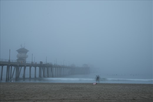 Foggy Laguna Beach Pier morning with surfers lining up for the perfect wave