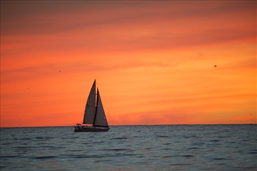 A sailboat passed through before the sun sets in the horizon