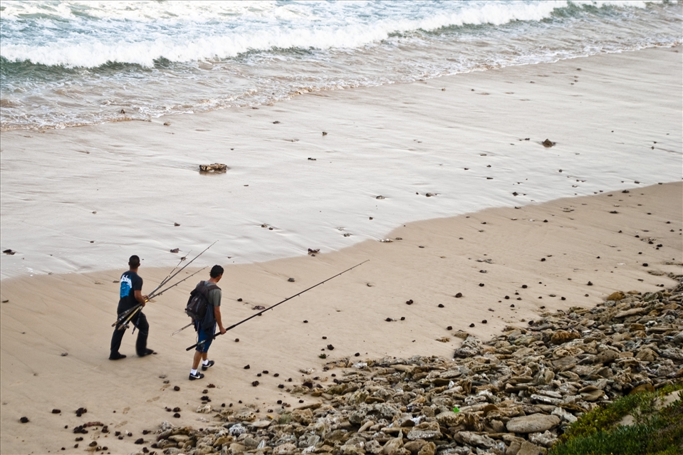 Two friends, Ruquet and Etienne, walk along the beach in search of the perfec