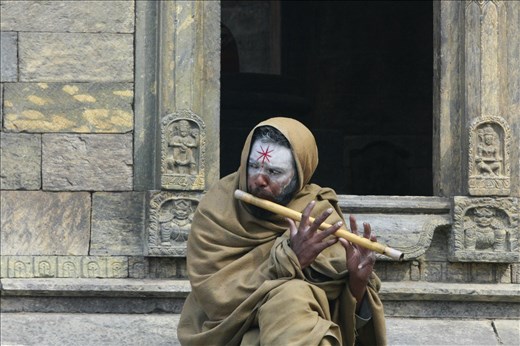 A Hindu man playing the flute at the Pashupatinath Temple.  The holisest Hindu temple in the world is located here in Kathmandu Nepal