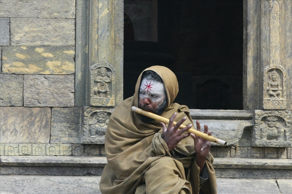 A Hindu man playing the flute at the Pashupatinath Temple.  The holisest Hindu temple in the world is located here in Kathmandu Nepal