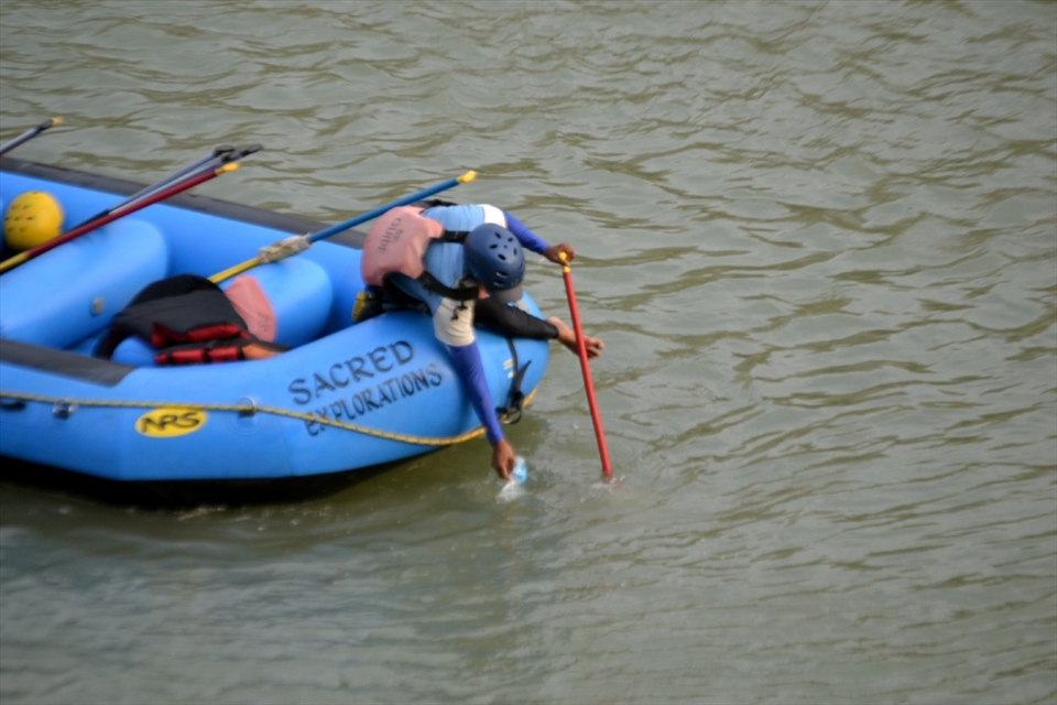 Sacred Science - A Raft Guide clearing up the litter thrown by others in the Ganges. People respect & regard Ganges as God. 