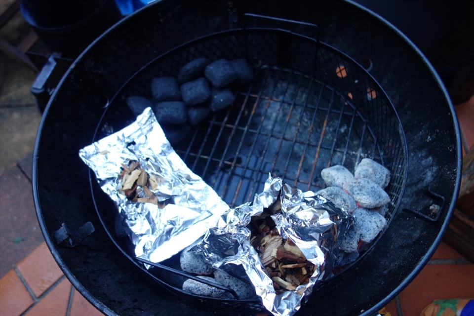 Setting up the smoker with a charcoal snake (for a slow burn and steady heat) and packets of wood chips for smoke.