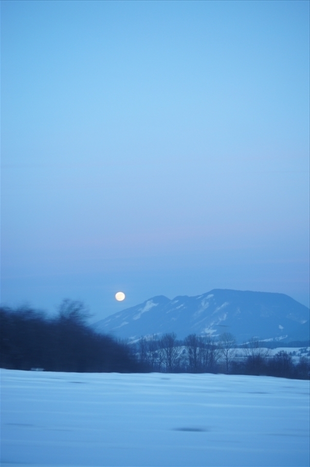 Traveling down the Autobahn at 100km/h, trees blurred, moon following behind