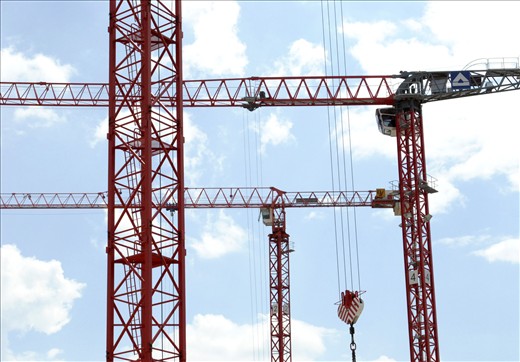 Several cranes are used to build the mall. A short moment lets them stop in perfect harmony. The loud construction noise is blanked out.