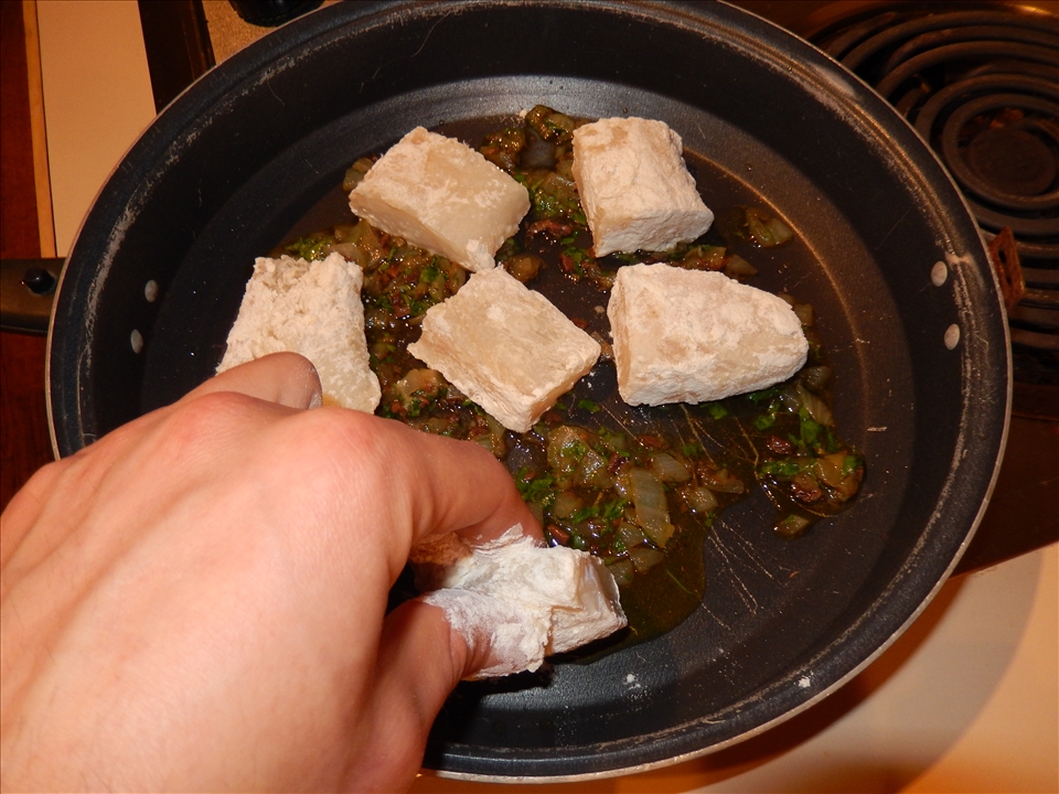 Placing the cod in the pan.